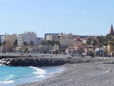 a beach with palm trees and buildings in the background at Apartment Cagnes Provencal by Interhome in Cagnes-sur-Mer