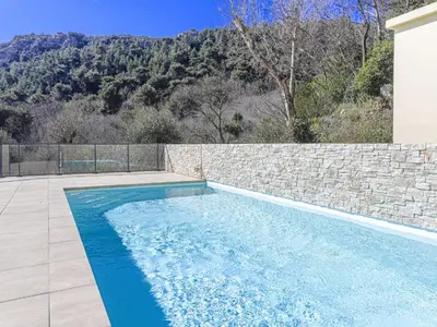a swimming pool in front of a stone wall at Apartment Prestige view by Interhome in Èze