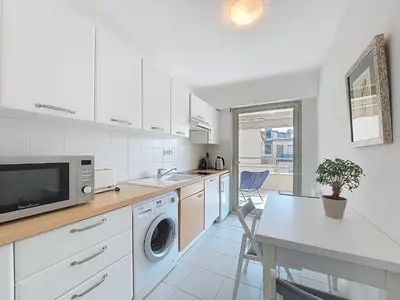 a kitchen with a washing machine and a table and a microwave at Nestor&Jeeves - LE BACCARA - Terrace - Central in Nice
