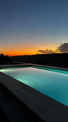 a large swimming pool with a sunset in the background at Maison C in Nice