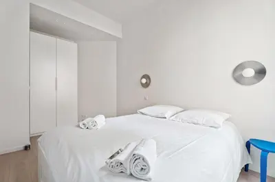 a white bedroom with a large white bed with towels on it at Appartement Ostave - Welkeys in Nice