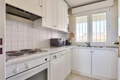 a kitchen with white cabinets and a stove top oven at T3 avec terrasse vue sur mer à 400m de la plage in Nice