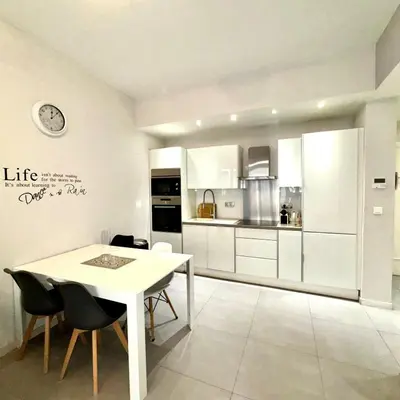 a white kitchen with a white table and chairs at Suite Doulce France FSHH in Nice