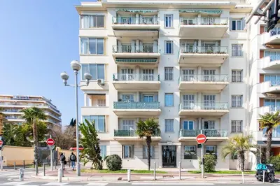 a tall white building with palm trees in front of it at #37 1BDR Bagatelle, Promenade, sea front Balcony & AC in Nice