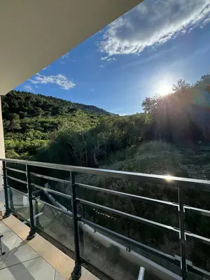 a view of a hill from a balcony with the sun shining at Appartement entre Monaco et Nice Calme et tout équipé in Èze