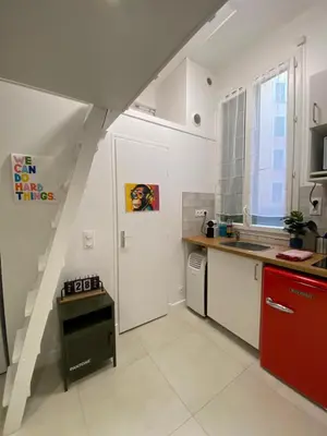 a kitchen with a staircase leading up to a kitchen with a red refrigerator at Studio Garibaldi in Nice