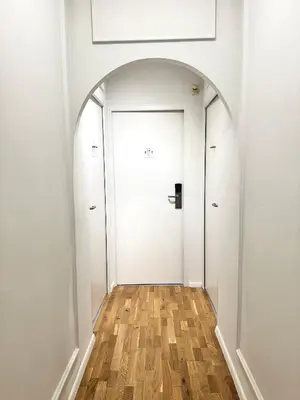 an arched hallway with a white door and wooden floors at Hotel La Citadelle in Villefranche-sur-Mer