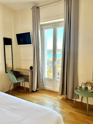 a hotel room with a bed and a large window at Hotel La Citadelle in Villefranche-sur-Mer