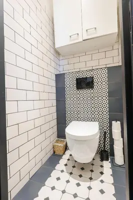 a bathroom with a white toilet and a black and white tiles at Magnifique Appartement 3P in Nice