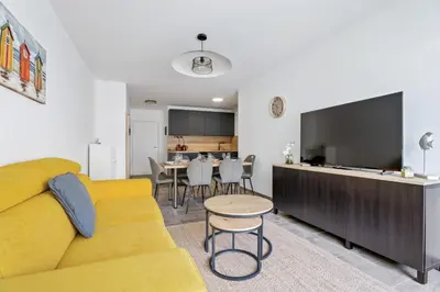 a living room with a yellow couch and a tv at Appartement Amandiers - Welkeys in Cagnes-sur-Mer