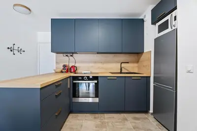 a kitchen with blue cabinets and wooden counter tops at Appartement Amandiers - Welkeys in Cagnes-sur-Mer
