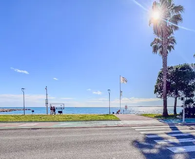a street with a palm tree and the ocean at Contemporary 2P Studio Just Steps from the Beach in Cagnes-sur-Mer