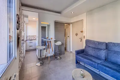 a living room with a blue couch and a kitchen at Contemporary 2P Studio Just Steps from the Beach in Cagnes-sur-Mer
