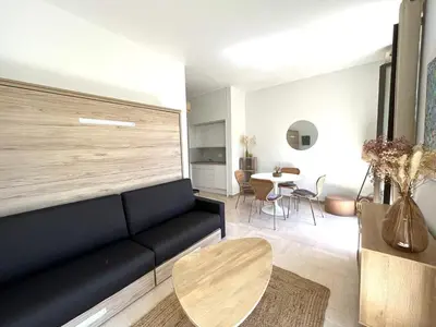 a living room with a black couch and a table at Beautiful studio with parking place Massena in Nice