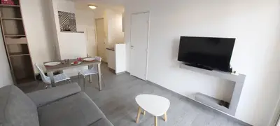 a living room with a couch and a table and a tv at Studio Cosy proche Carlone, balcon in Nice