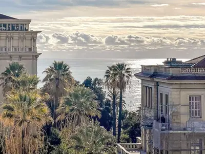 a view of a building and palm trees and the ocean at Apartment Le Mirazur by Interhome in Nice