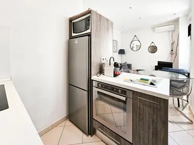 a kitchen with a stainless steel refrigerator and a table at Fontaine 4 Pers AC WiFi in Nice