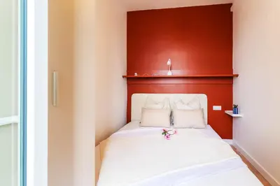 a small bedroom with a bed with a red headboard at TERRACOTTA AP4457 By Riviera Holiday Homes in Villefranche-sur-Mer