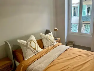 a bed with white pillows and an orange blanket at Suite Massena in Nice
