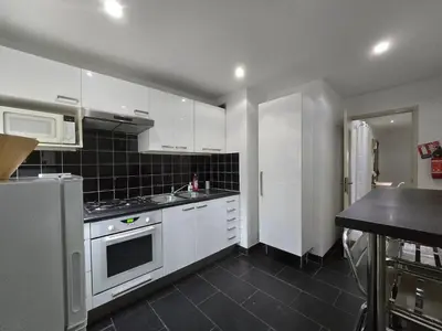 a kitchen with white cabinets and a stove top oven at Large T2 50m from the beaches in Nice