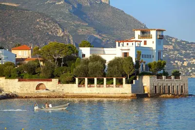 a small boat in the water in front of a building at Magnifique T3 wifi, garage et climatisation à 5 min de la plage in Beaulieu-sur-Mer