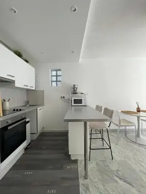 a kitchen with white cabinets and a table and chairs at apppartement avec terrasse - 2 à 4 personnes in Nice