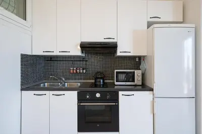 a kitchen with white cabinets and a sink and a microwave at Appartement Eze Village proche Monaco fabuleuse vue mer et vieux village in Èze