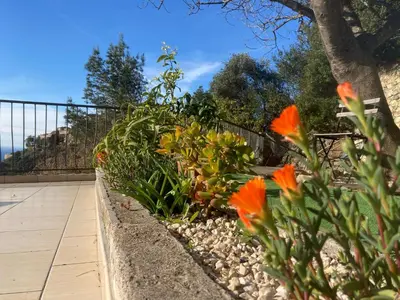 a garden with orange flowers and a fence at Appartement Eze Village proche Monaco fabuleuse vue mer et vieux village in Èze