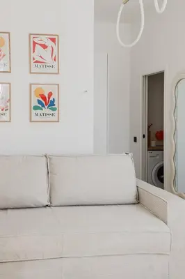 a white couch in a white room with pictures on the wall at Modern 3BR Duplex Near Nice Port & Old Town | By Airnest in Nice