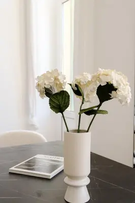 a white vase with white flowers on a table at Fancy 3BR Duplex Near Nice Port & Old Town | By Airnest in Nice