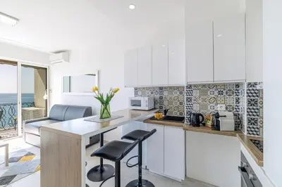 a kitchen with white cabinets and a counter with stools at Sea View - Lovely Studio Promenade des Anglais in Nice