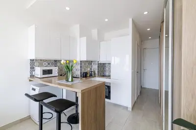 a kitchen with white cabinets and a counter with stools at Sea View - Lovely Studio Promenade des Anglais in Nice