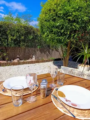 a wooden table with plates and glasses on it at Fabron studio et Résidence de Luxe avec Piscine in Nice