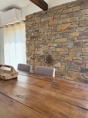 a stone wall with two chairs and a wooden table at maison de charme piscine au bord de mer in Cagnes-sur-Mer