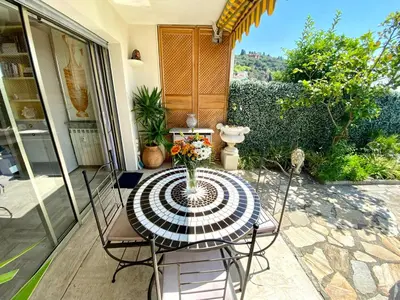 a table with a vase of flowers on a patio at Studio Bellevue in Villefranche-sur-Mer