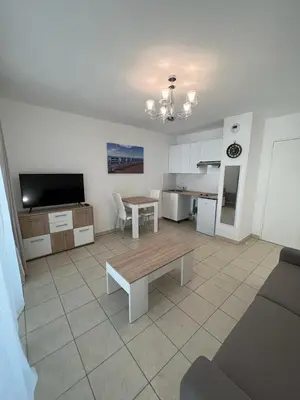 a living room with a table and a kitchen at Sunny studio with Terrace in Nice