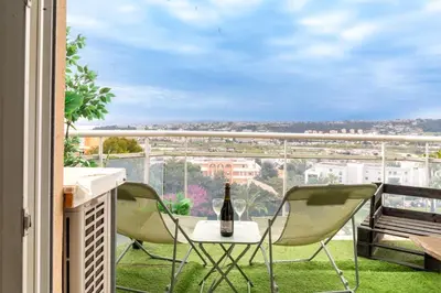 a balcony with two chairs and a table with a bottle of wine at Studio équipé dans une résidence avec piscine à 10mn du centre ville in Nice