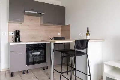 a kitchen with a counter and a bar with two chairs at Studio équipé dans une résidence avec piscine à 10mn du centre ville in Nice