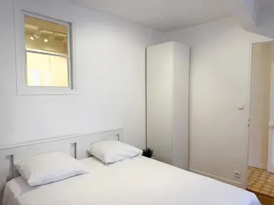 a white bedroom with a bed and a window at Charmant 2 pièces proche mer in Nice