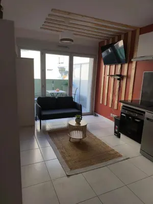 a living room with a couch and a table at Studio calme et paisible, climatisé avec terrasse au dernier étage, 100m du tramway et 20 min de la promenade des anglais in Nice