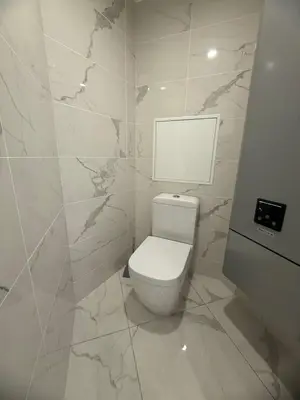 a bathroom with a white toilet and marble walls at Magnifique 3 pièces à 100m de la mer in Nice