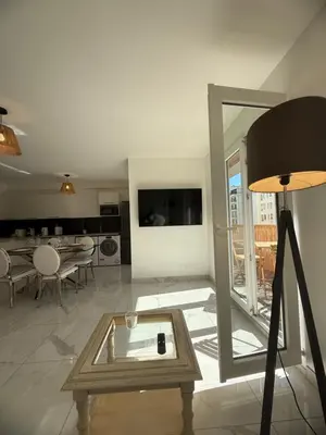 a living room with a table and a tv at Magnifique 3 pièces à 100m de la mer in Nice