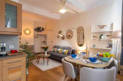 a kitchen and living room with a table and a couch at Charming flat, fully equipped, air conditioning, beach only 300m - LA LOGE in Nice