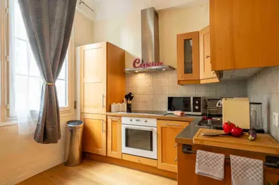 a kitchen with wooden cabinets and a stove top oven at Charming flat, fully equipped, air conditioning, beach only 300m - LA LOGE in Nice