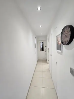 a hallway with white walls and a clock on the wall at Sunny Prom Studio in Nice