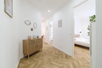 a white room with a bed and a wooden floor at Large & Confort 2 Bdr Renovated in Nice