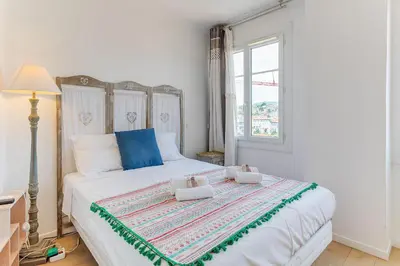 a bedroom with a large white bed with blue accents at LE PAIROLIERE AP4461 by Riviera Holiday Homes in Nice