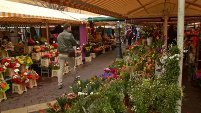 a man walking through a market filled with flowers at Nestor&Jeeves - DOLCE VITA STUDIO - Balcon - Central in Nice