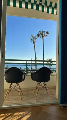 two chairs sitting on a balcony with a view of the beach at Carre d Or Face a la Mer in Nice