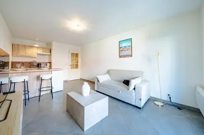 a living room with a white couch and a kitchen at Cozy 2P Port de Nice garage in Nice